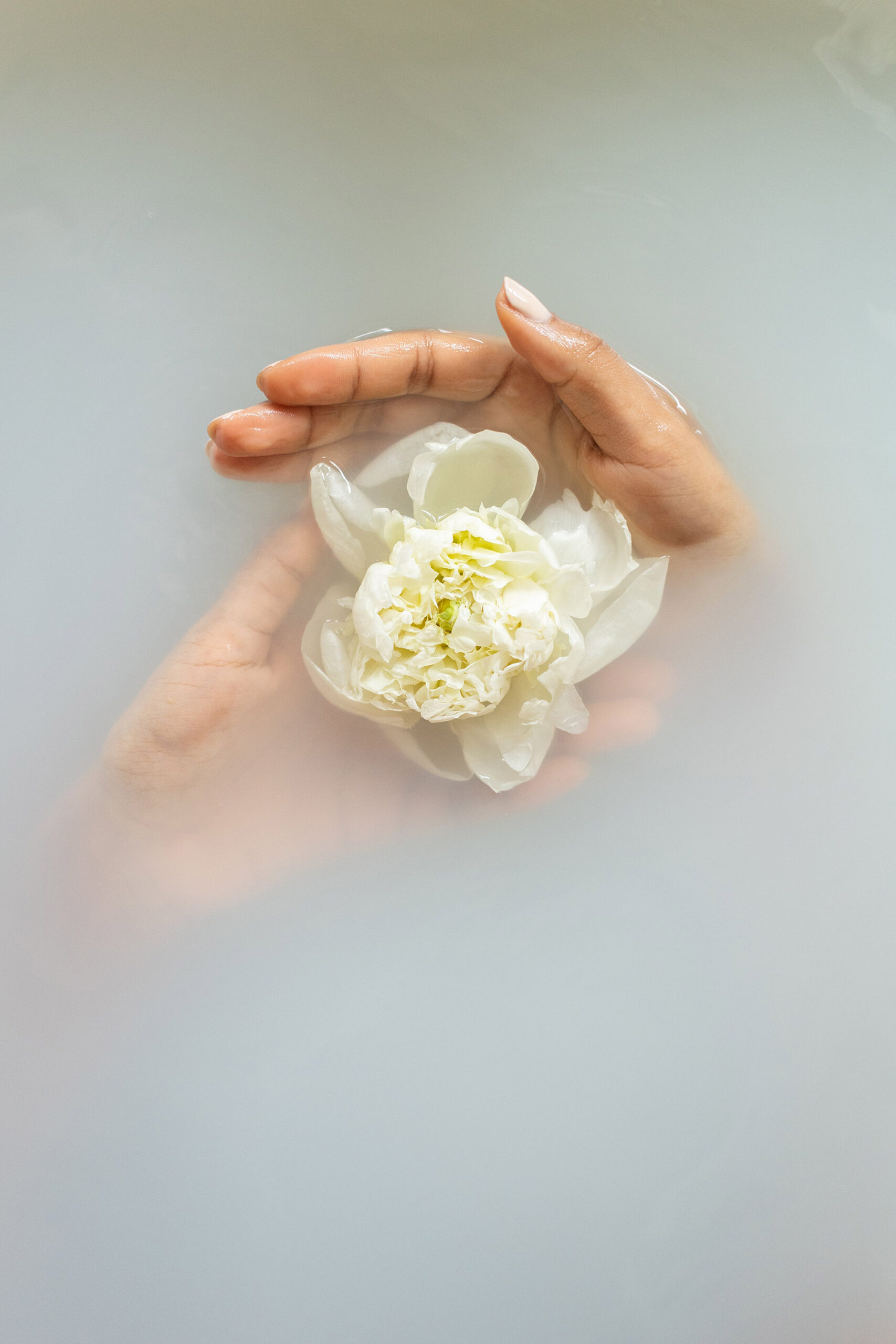 manicured hands and flower in water